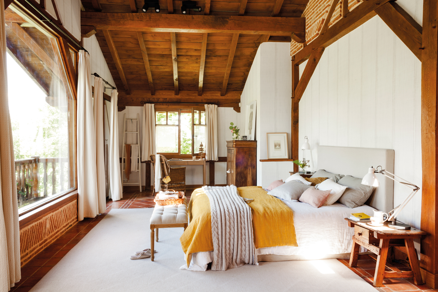 large open bedroom with exposed wood beams and rustic refined style with warm accents
